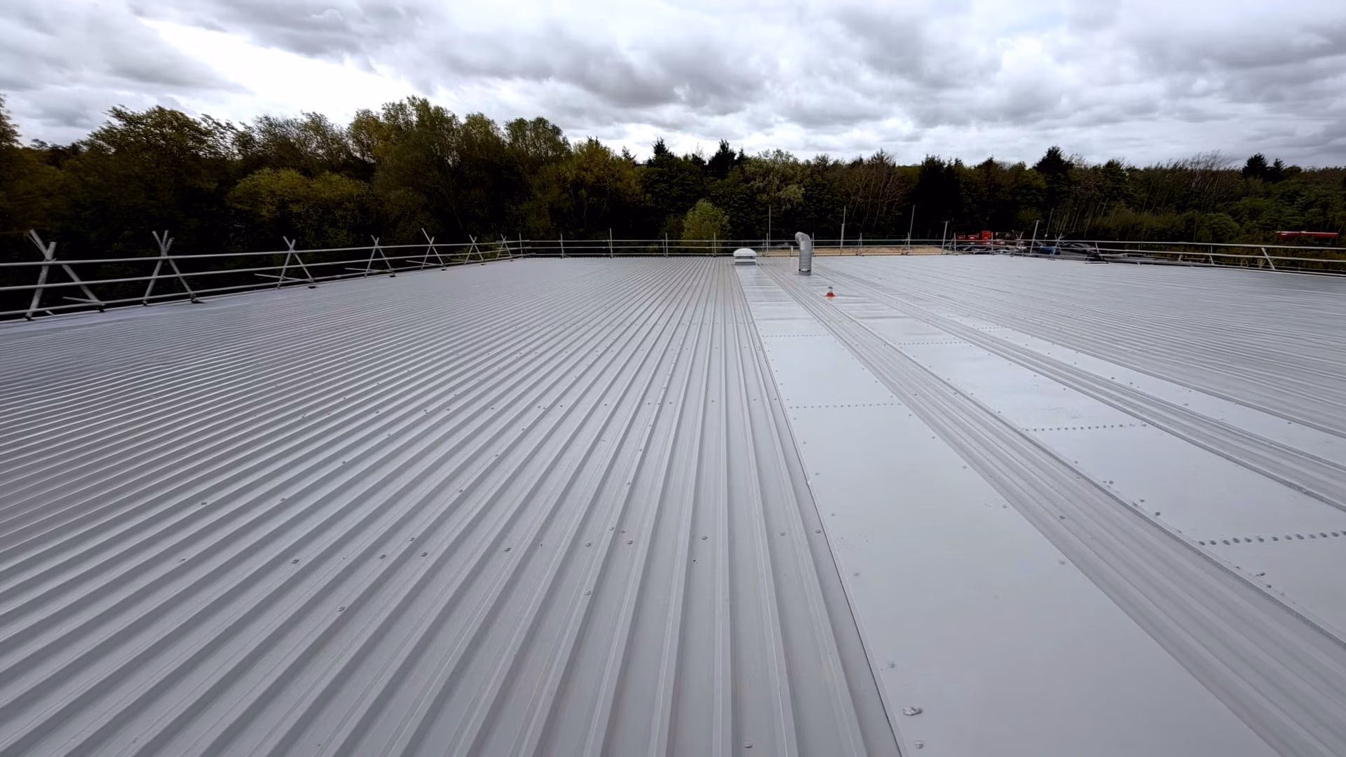 flat-metal-roofing-installation-with-surrounding-scaffolding Large flat metal roofing installation with surrounding scaffolding