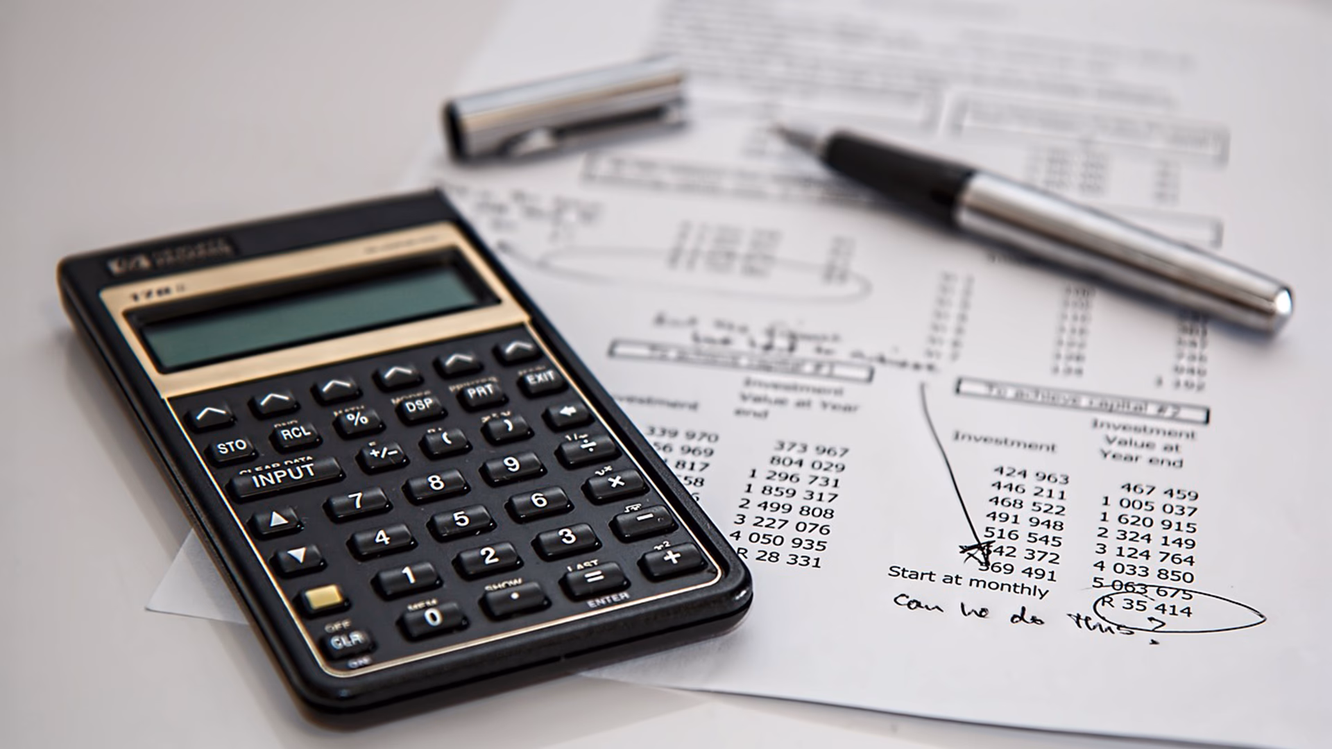 Open pen and calculator above financial documents representing financial complexity