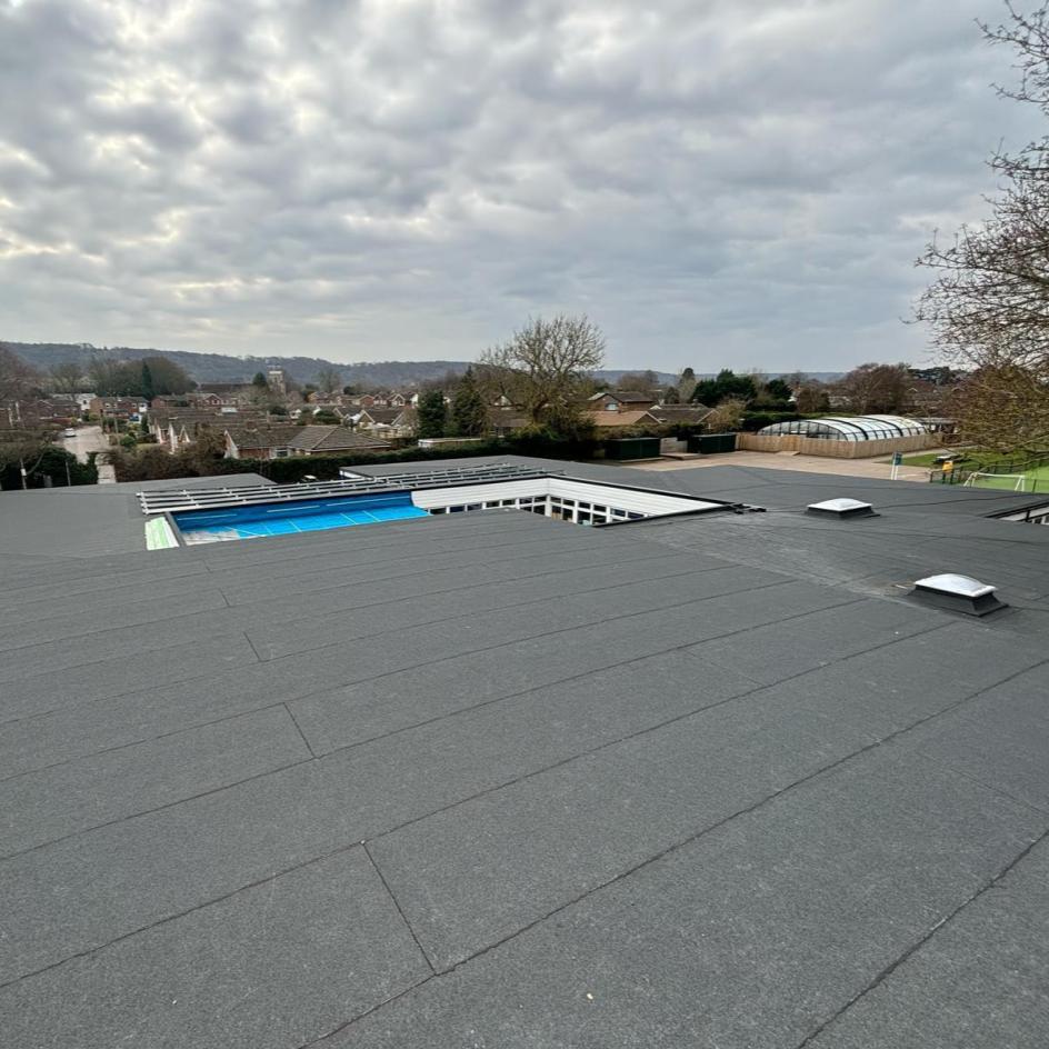Completed flat roof refurbishment at St Andrews School showing new felt roofing system across multiple roof levels with rooflights and internal courtyard area.