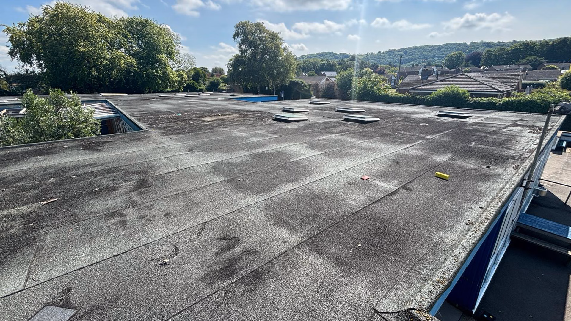 Existing flat roof at St Andrews School in Oxfordshire showing aged roofing membrane and rooflights prior to commercial roof refurbishment works.