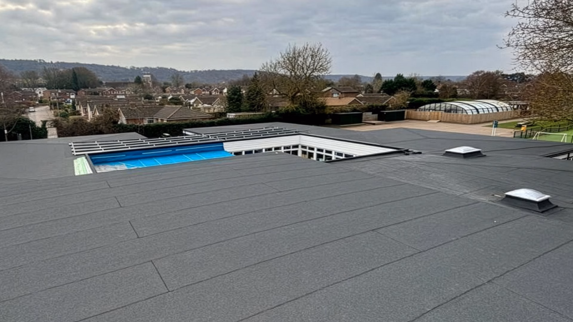Completed flat roof refurbishment at St Andrews School showing new felt roofing system across multiple roof levels with rooflights and internal courtyard area.