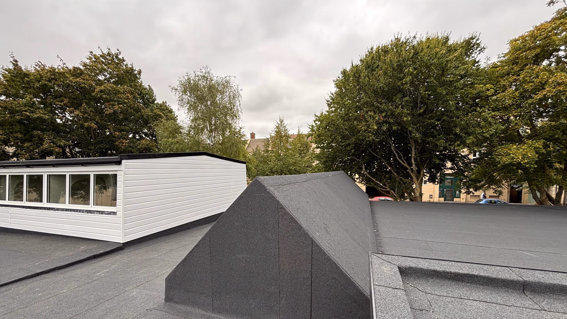 Torch-applied felt flat roof system with finished upstand detail at Whitney Library commercial roofing project.